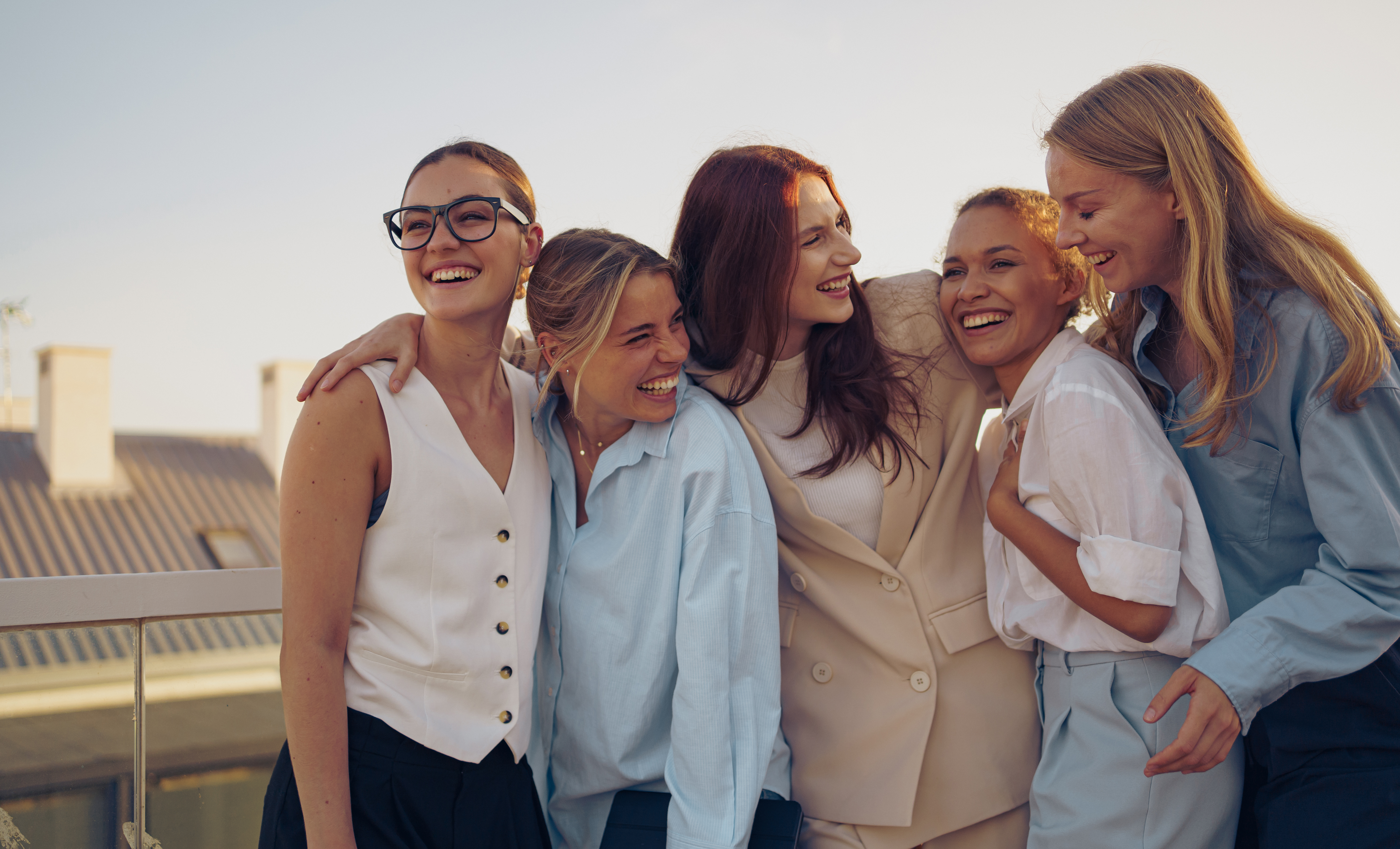 Five close friends share a delightful and joyful moment outdoors, beautifully captured against a stunning sunset